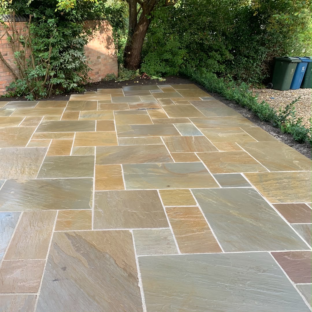 Indian sandstone patio laid in a random pattern in a leafy garden