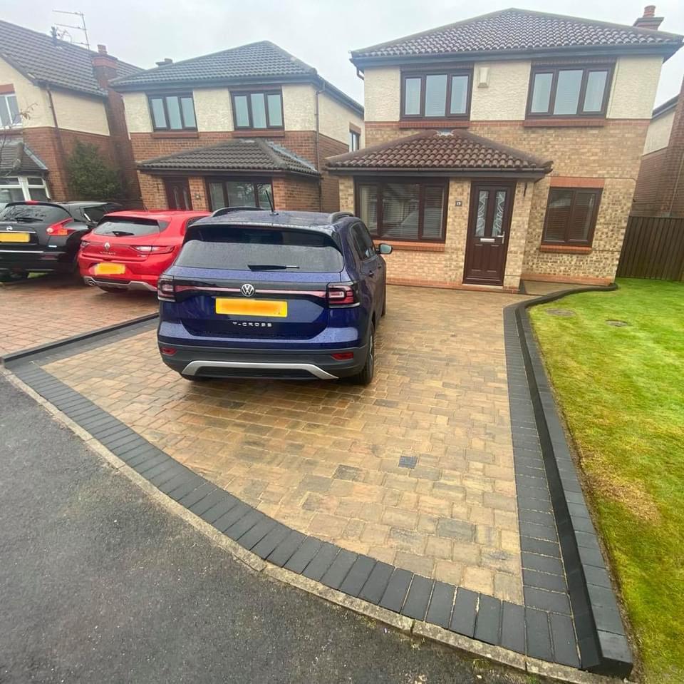 Buff block paved driveway with a charcoal border in front of a detached house