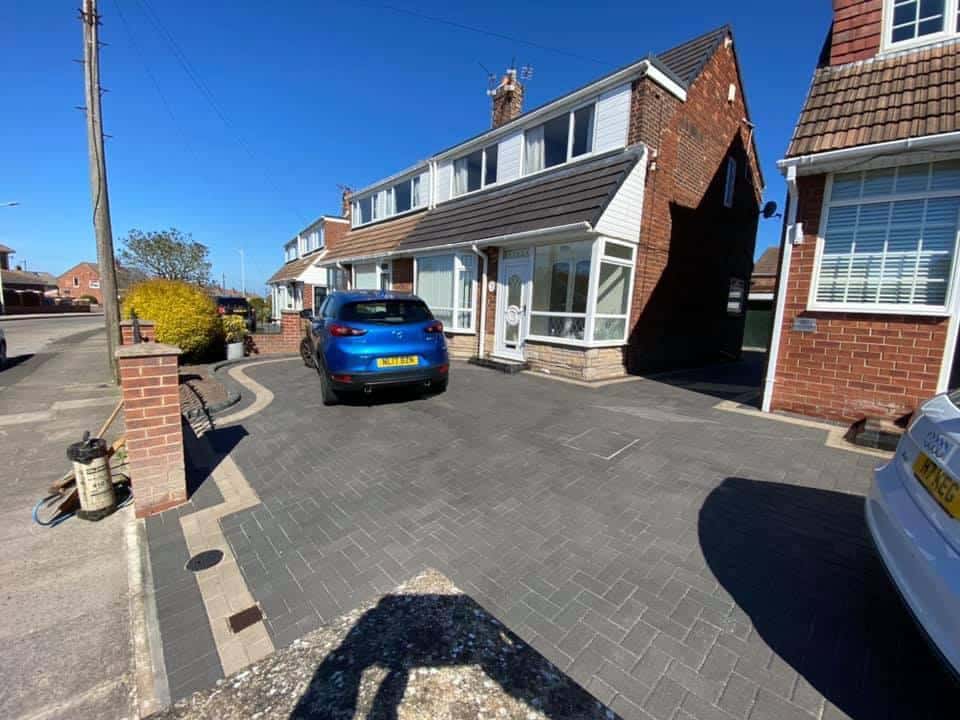 Charcoal block paved driveway with a brick pier on a residential street
