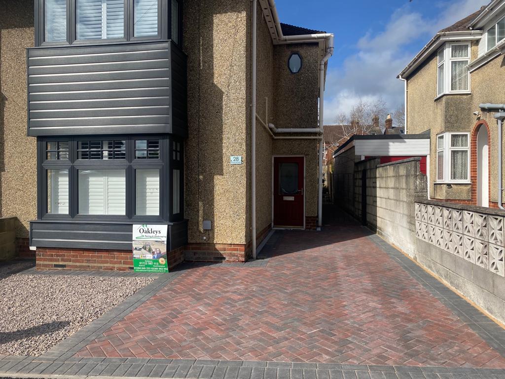 Red herringbone block paved front driveway laid by Oakleys, with an Oakleys board on the gravel